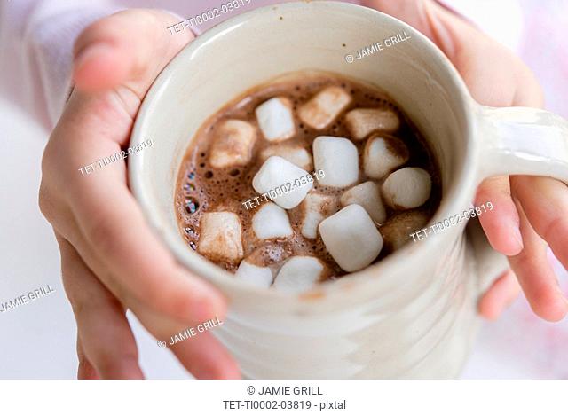 Hands of girl holding hot chocolate with marshmallows