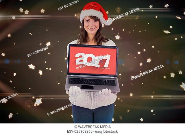 Composite image of smiling brunette in santa hat showing her laptop