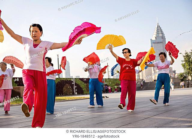 Chinese women perform early morning fan exercise on the Bund Shanghai, China
