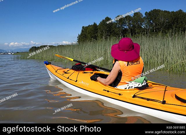 Woman kayaking on the Fraser River, Ladner, BC, Canada