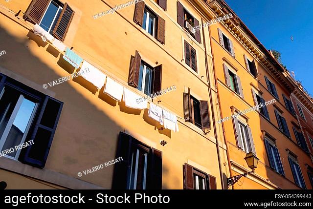 bottom view with wide angle of ancient stately buildings in the center of rome. In a building there are clothes hanging out to dry in the sun