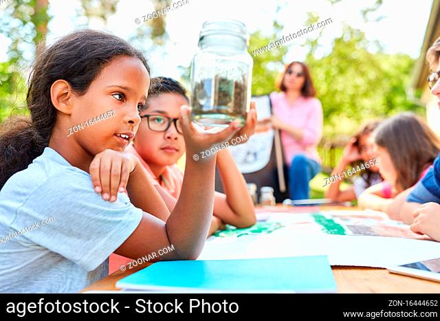 Mädchen mit Bodenprobe im Glas im Biologie Unterricht im Ferienkurs der Sommerschule
