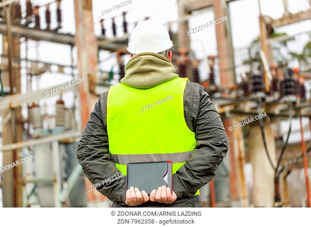 Electrician with tablet PC in electrical substation