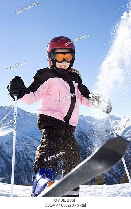 Young girl flicking snow off her skis