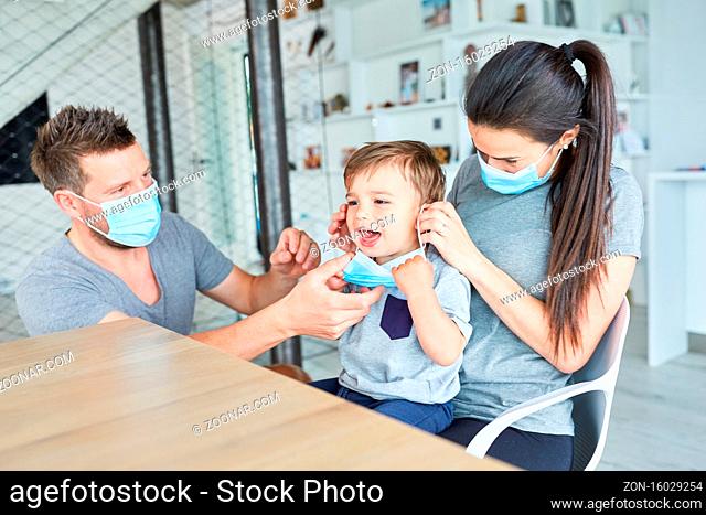 Eltern und weinendes Kind mit Mund-Nasen-Schutz wegen Coronavirus und Covid-19