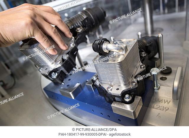 17 April 2018, Germany, Ludwigsburg: A staff member of automotive supplier and car filter specialist Mann+Hummel, works on a module for oil regulation and...