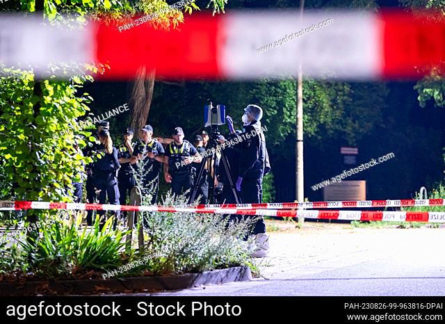 26 August 2023, Hamburg: Forensic technicians work with a 3D scanner alongside other police officers near the cordoned-off crime scene