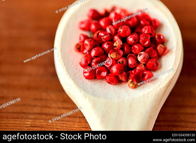close up of pink peppercorns on wooden spoon