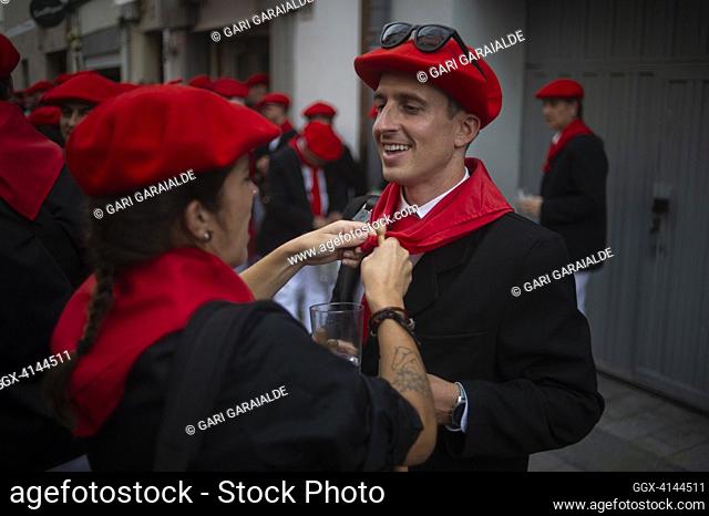 A woman helps a man tie his scarf around his neck during the traditional 'Alarde de San Marcial' arm parade. Irun (Spain). June 30, 2023