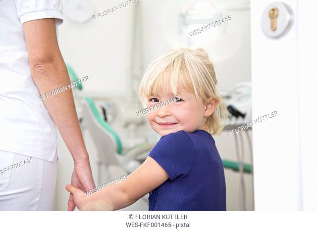 Dental assistant holding girl's hand before treatment
