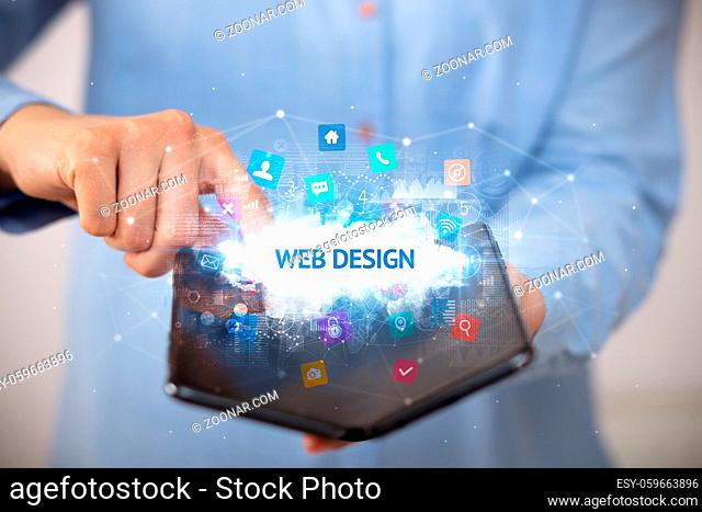Businessman holding a foldable smartphone with WEB DESIGN inscription, technology concept