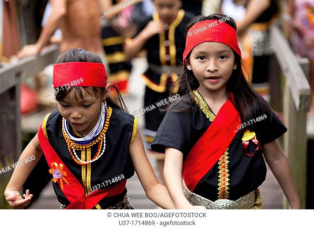 Young Bidayuh girls in traditional costumes running around Anna Rais Long House during Selamat Gawai Harvest Festival