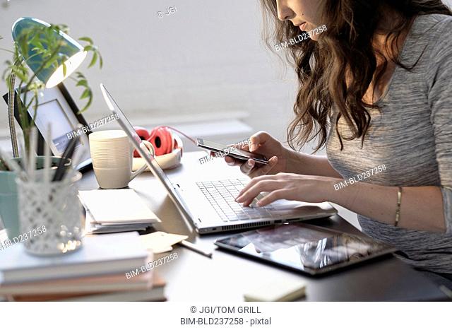 Hispanic businesswoman using technology in office