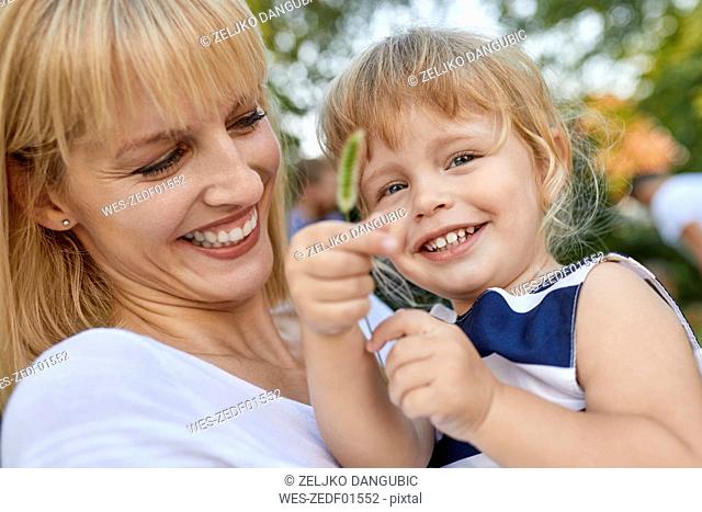 Happy mother with her daughter holding a stalk outdoors