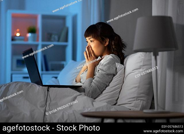 stressed woman with laptop working in bed at night