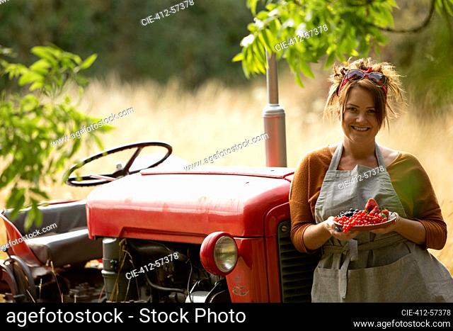 Retrato mujer orgullosa feliz en el tractor con grosellas rojas frescas