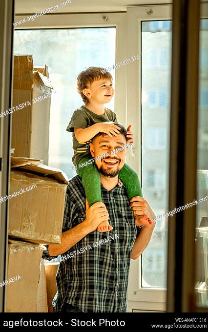 Smiling father carrying boy on shoulders at home