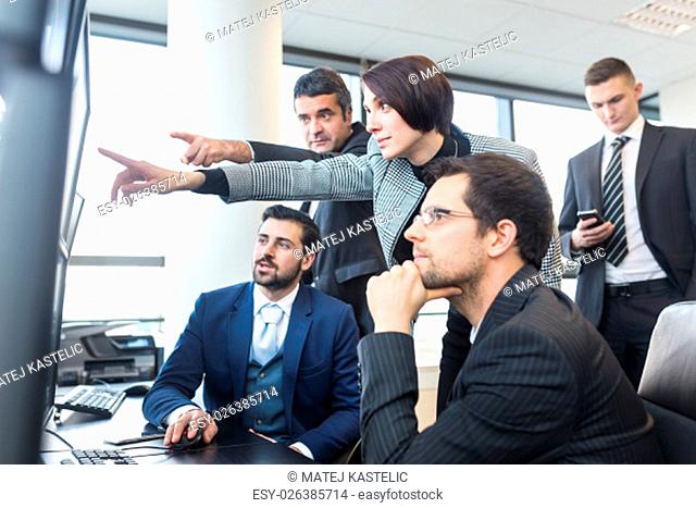 Business team looking at data on multiple computer screens in corporate office. Business people trading online. Business, entrepreneurship and team work concept
