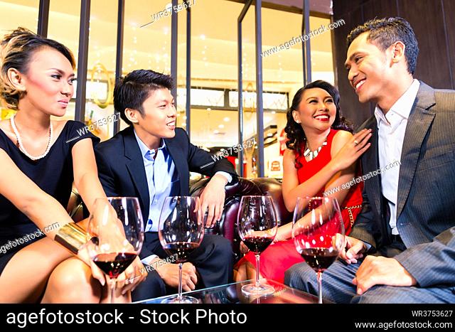 Asian friends chatting and drinking red wine