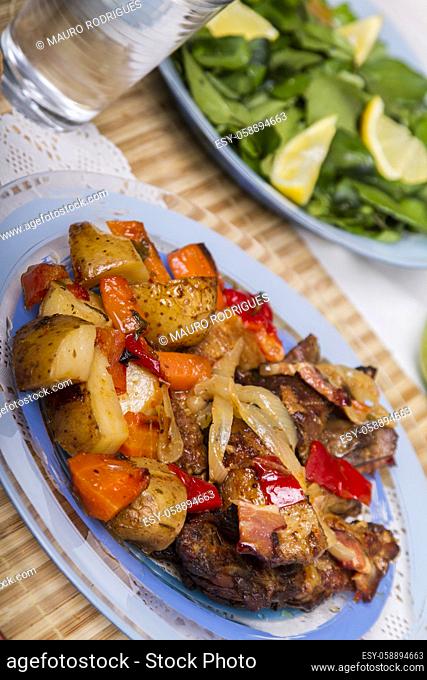 Close up view of oven baked meat with potatoes, and watercress salad
