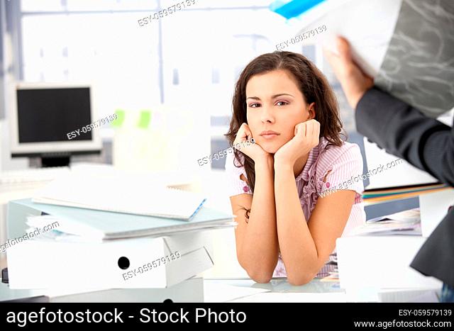 Attractive girl sitting among folders in bright office desperately, having too much work