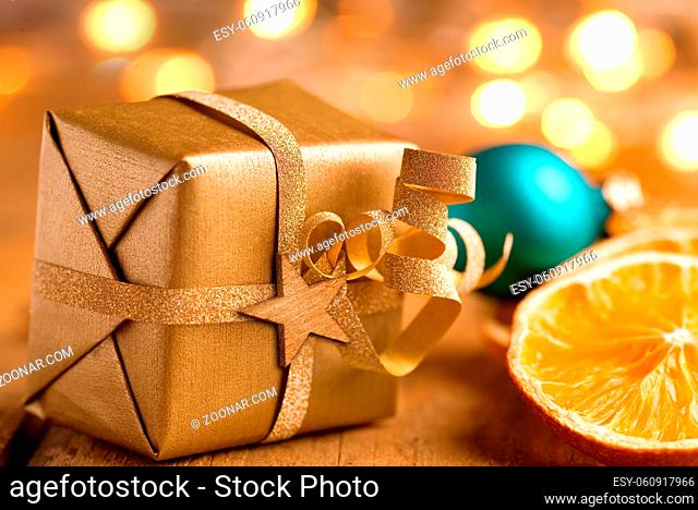 Weihnachten - Goldenes Päckchen mit Stern und Lichtern auf Holz