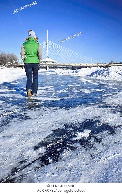 Woman strolling the frozen Red River in front of the Esplanade Riel Bridge. The Forks, Winnipeg, Manitoba, Canada
