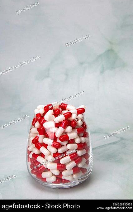 Filled glass with capsules pills for medication. drugs or vitamin, assorted pharmaceutical medicine tablets, in jar, health, business