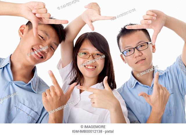 Teenagers gesturing with finger frame and smiling at the camera together