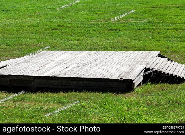 low wooden platform for performances in the village, green grass