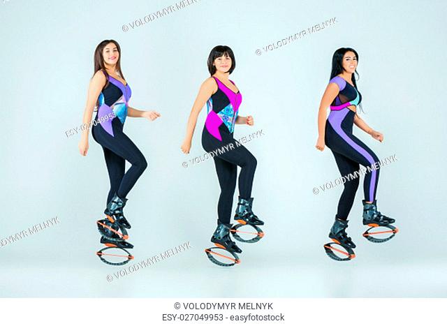 The group of young girls, jumping on kangoo training on gray