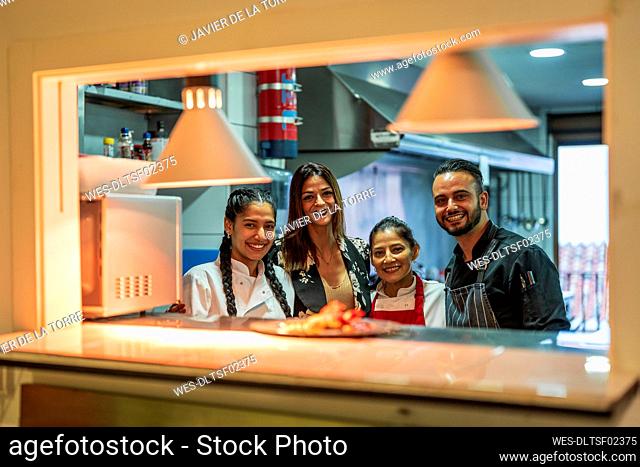 Smiling manager with kitchen team in restaurant