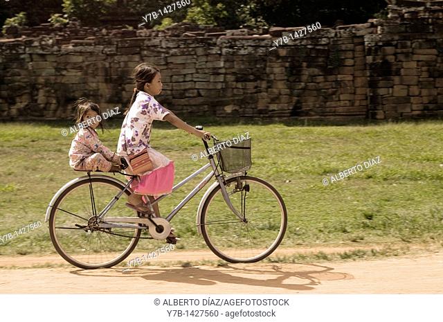 Girls riding bikes through the temples of Angkor Wat