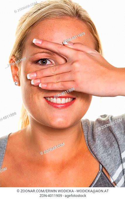 Eine junge Frau blickt durch die Finger ihrer Hand. Symbolfoto für Durchblick und Flirt