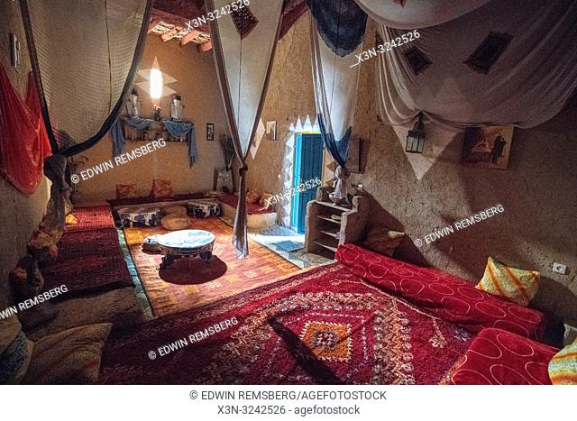 Interior living space with hung fabrics through out in traditional mud-built brick house in Tighmert Oasis, Morocco