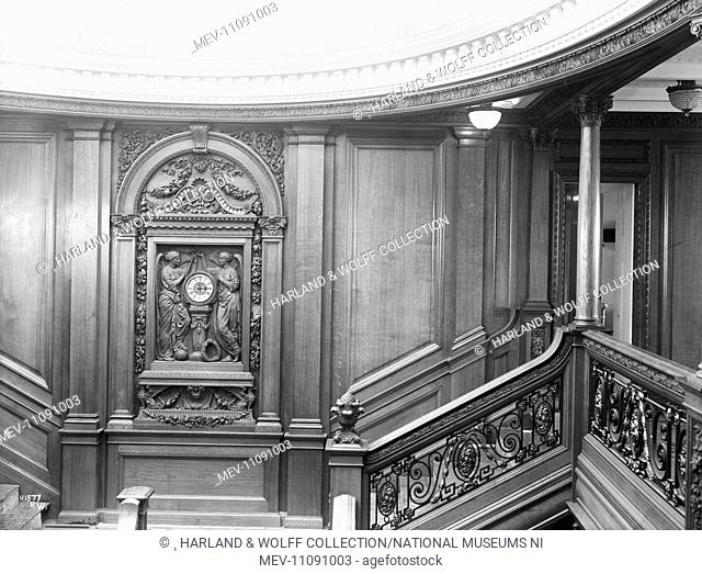 Landing of first class main staircase, with carved panel incorporating clock and symbol of honour and glory crowning time. Ship No: 400. Name: Olympic