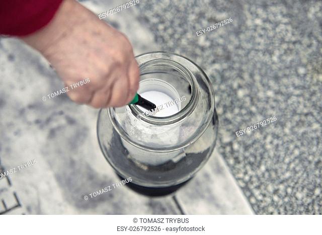old woman at cemetery is lighting a candle