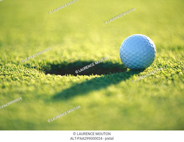 Golf ball at edge of hole, close-up