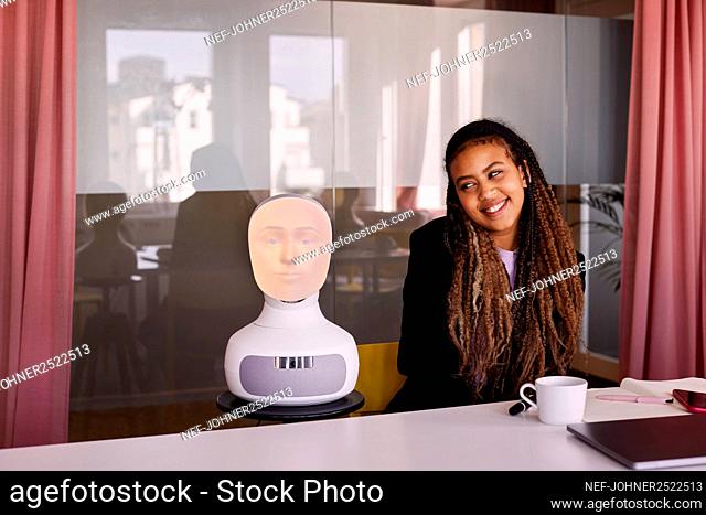 Businesswoman looking at robot voice assistant