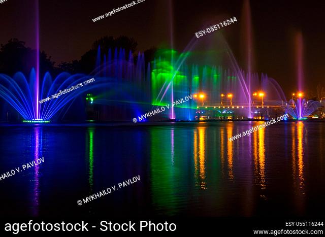 Summer night in the city. Fountain on the river with lights