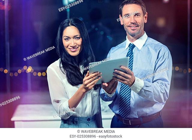 Portrait of businessman and colleague holding digital tablet