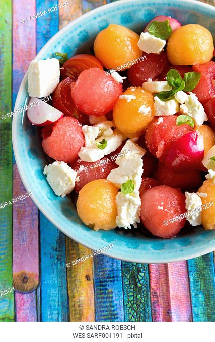 Melon salad with feta, tomato and red radish in bowl