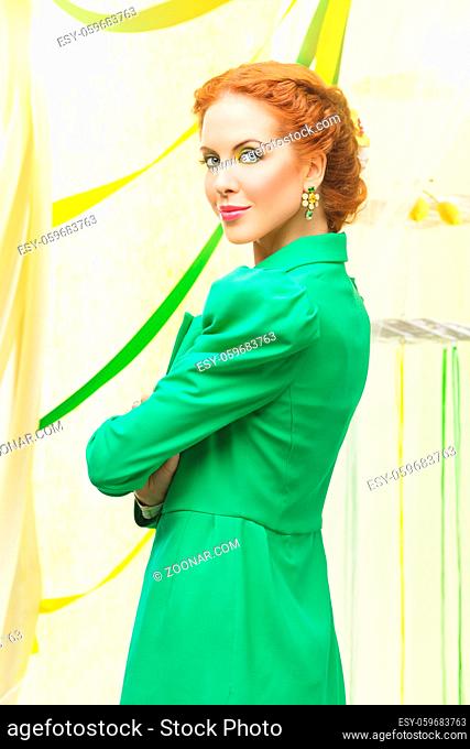 Beautiful young woman with braided red hair standing in green long jacket
