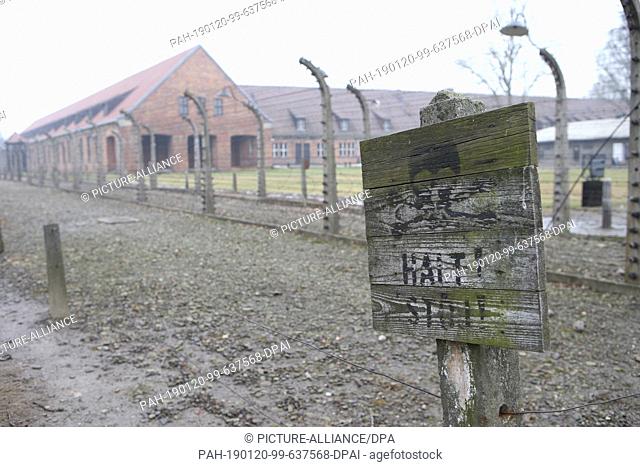 27 January 2018, Poland, Oswiecim: A sign with the inscription ""CAUTION: High Voltage Danger to Life"" is attached to a post in front of a wire fence in the...
