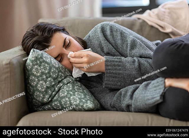 sad crying woman with tissue lying on sofa at home