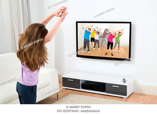 Girl Looking At Television While Doing Exercise At Home