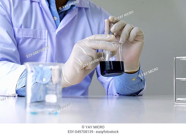 Male medical or scientific laboratory researcher performs tests with blue liquid in laboratory. equipment science experiments concept