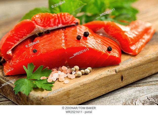 Fresh Copper River Salmon fillets on rustic wooden server with spices and herbs