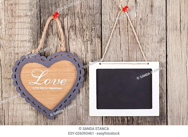 Empty wooden blackboard sign and heart shape frame with love text on wooden background. valentines day card concept