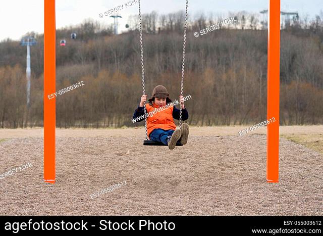 Joyful boy on the playground on a swing